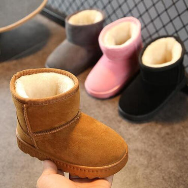Brown children's snow boot held in hand with other boots in the background